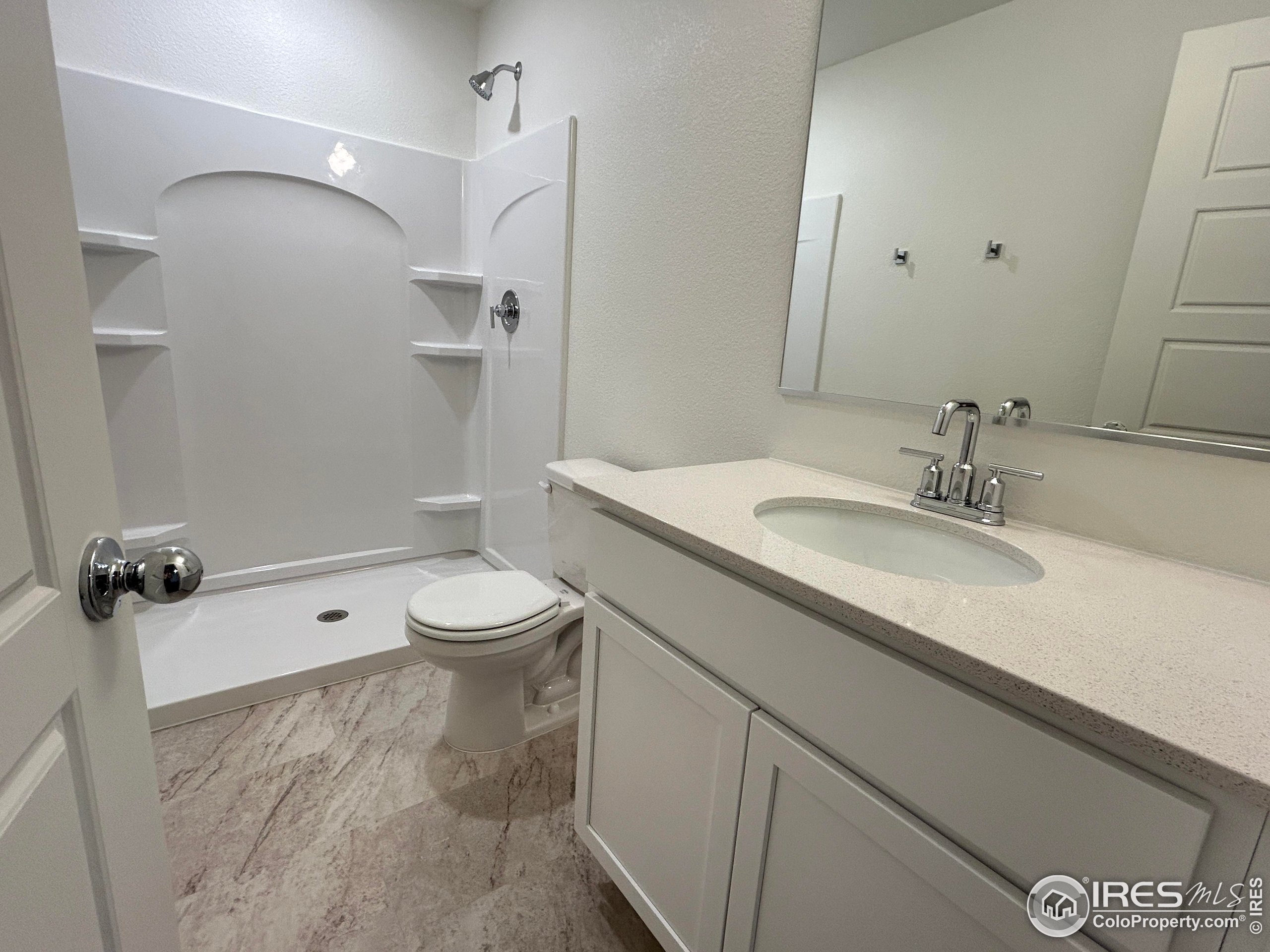 3905 Net Street Evans, CO 80620 - Photo 7 of 15 a bathroom with a granite countertop sink a toilet a mirror and shower