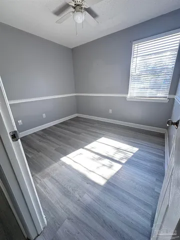 a view of empty room with wooden floor and fan