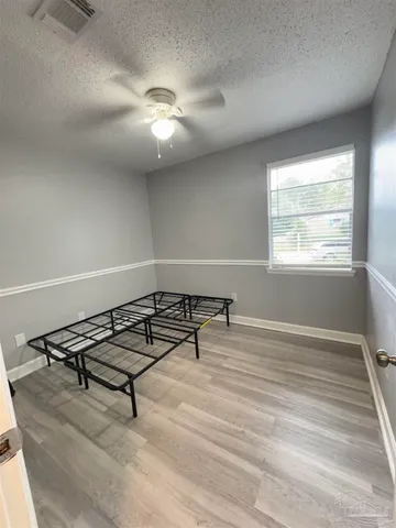 an empty room with windows and ceiling fan