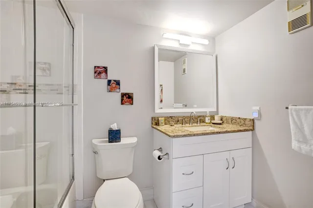 a bathroom with a granite countertop toilet sink and mirror
