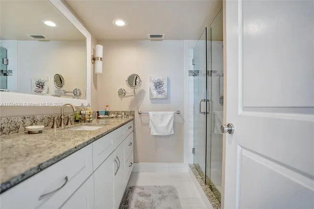a bathroom with a granite countertop sink mirror and shower