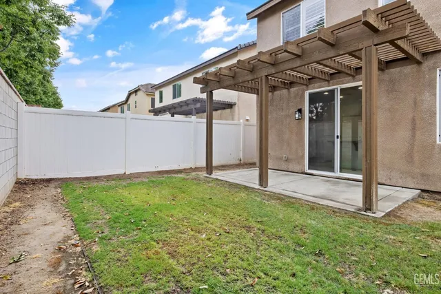 a view of a white house with a big yard plants and large tree
