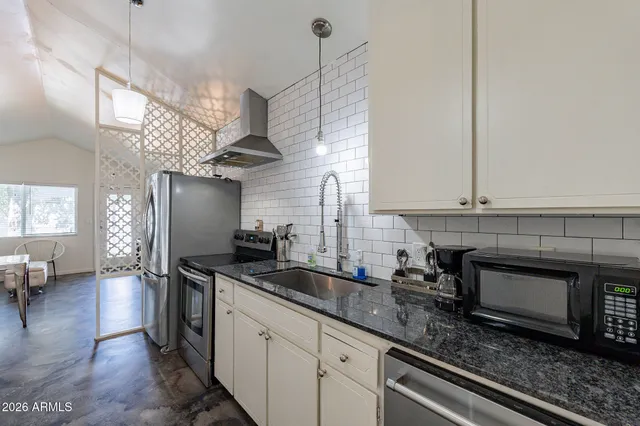 a kitchen with stainless steel appliances granite countertop a sink a stove and a wooden floors