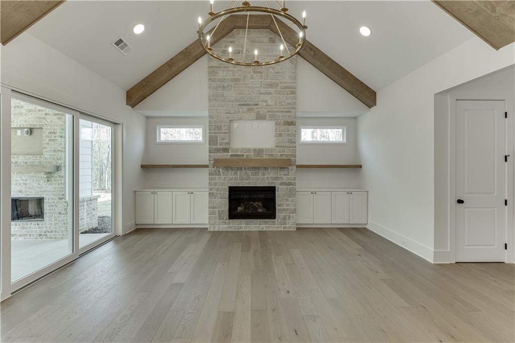 128 Ivey Trace Pendergrass, GA 30567 - Photo 11 of 57 an empty room with wooden floor a fireplace and windows