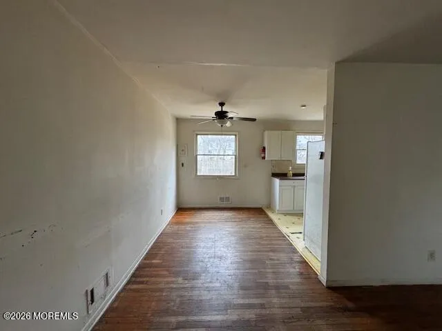 a view of a hallway with wooden floor and a kitchen