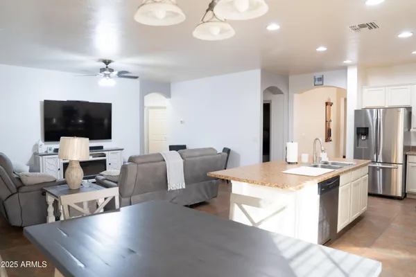 a large living room with stainless steel appliances kitchen island granite countertop a stove and a view of living room