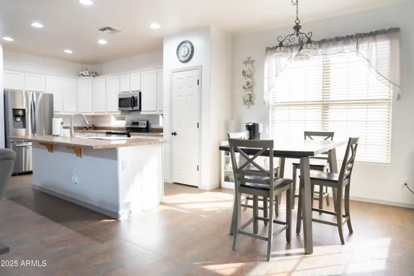 a kitchen with stainless steel appliances kitchen island granite countertop a stove a refrigerator a sink a dining table and chairs with wooden floor