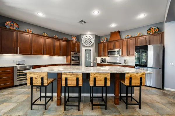 a kitchen with stainless steel appliances granite countertop table chairs and a refrigerator