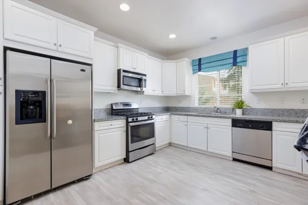 a kitchen with granite countertop a refrigerator stove top oven and sink