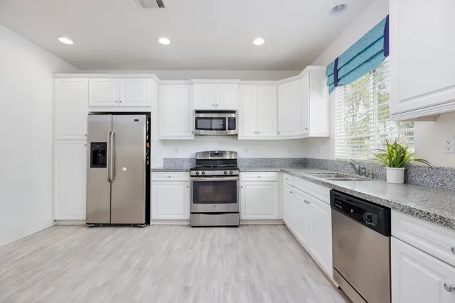 a kitchen with stainless steel appliances granite countertop a stove a sink and a refrigerator
