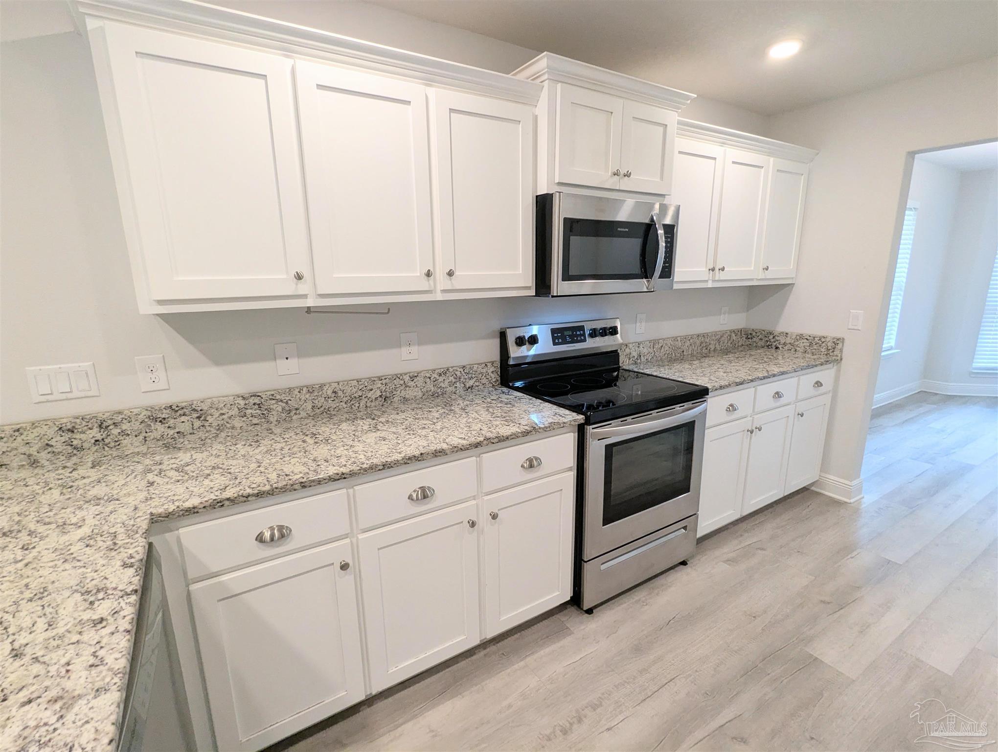 4723 Frances Street Pace, FL 32571 - Photo 12 of 41 a kitchen with granite countertop white cabinets white stainless steel appliances and a sink