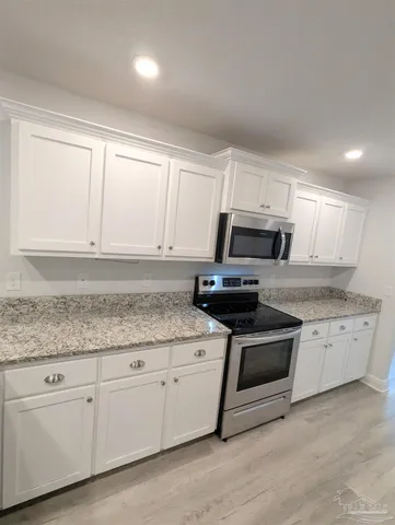 a kitchen with granite countertop white cabinets white stainless steel appliances and a sink