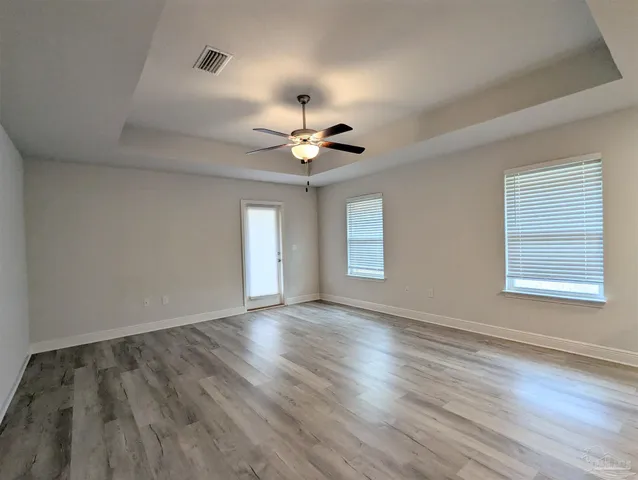 an empty room with wooden floor and windows