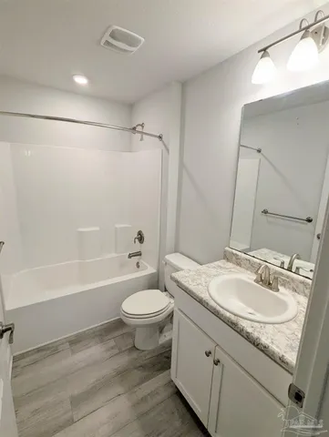 a bathroom with a granite countertop sink toilet a mirror and bathtub