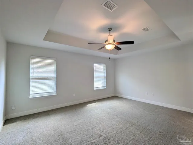 an empty room with a chandelier fan and windows