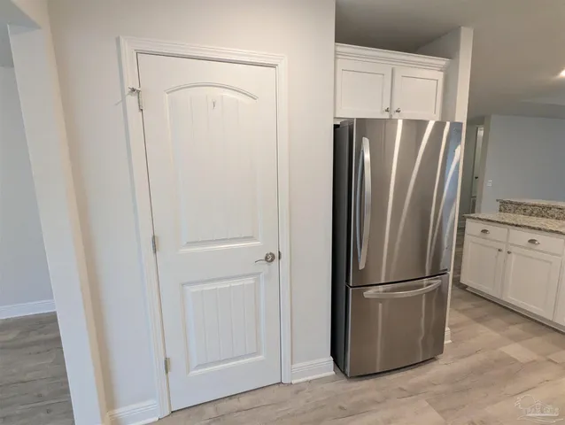 a view of a refrigerator in kitchen and white cabinets