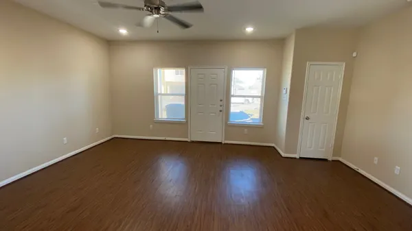 an empty room with wooden floor and windows