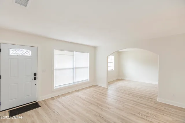 an empty room with wooden floor and windows