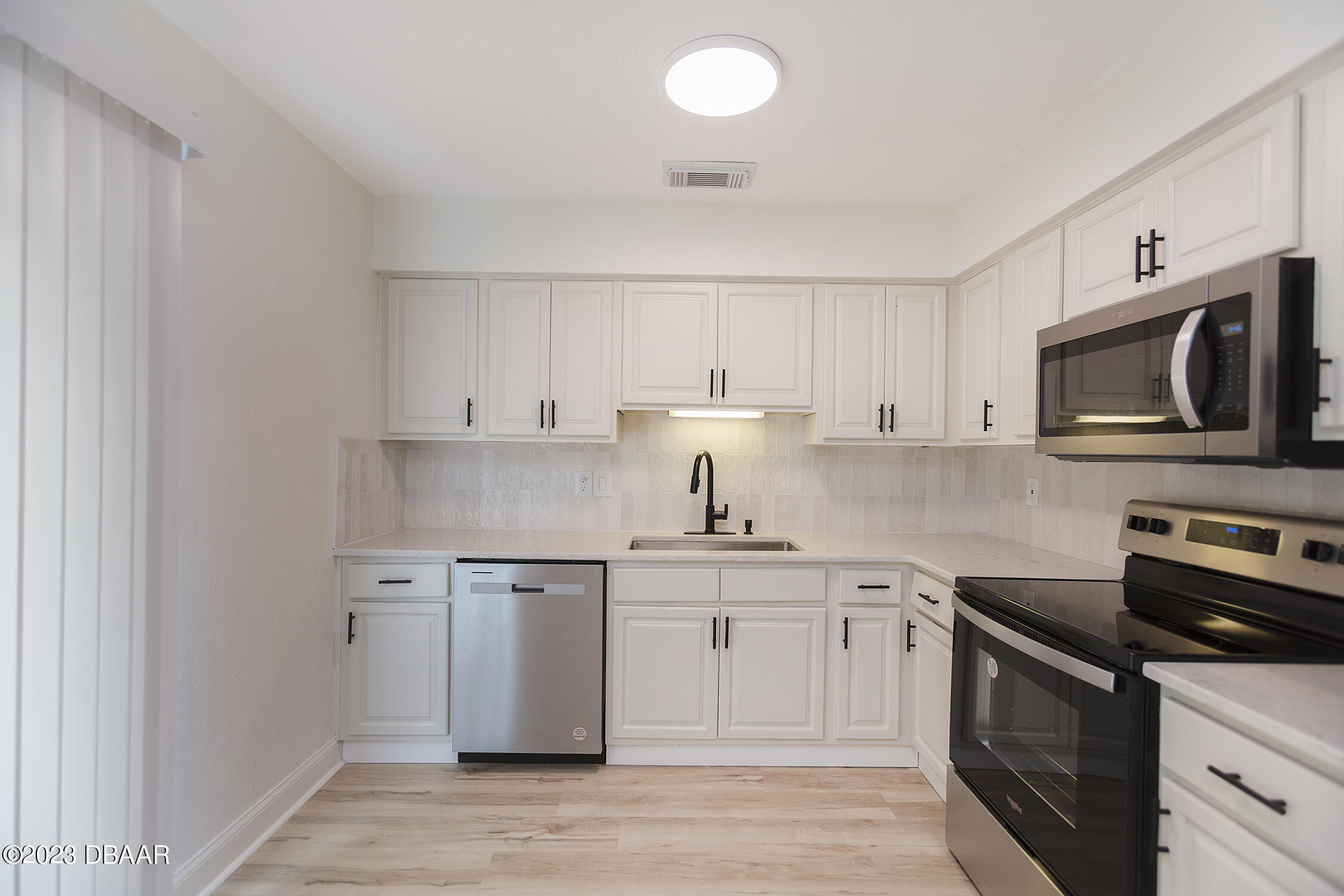 489 Wiltshire Boulevard Port Orange, FL 32127 - Photo 19 of 40 a kitchen with stainless steel appliances granite countertop a sink a stove top oven and white cabinets