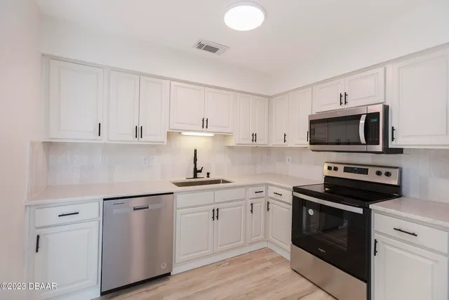 a kitchen with white cabinets and stainless steel appliances