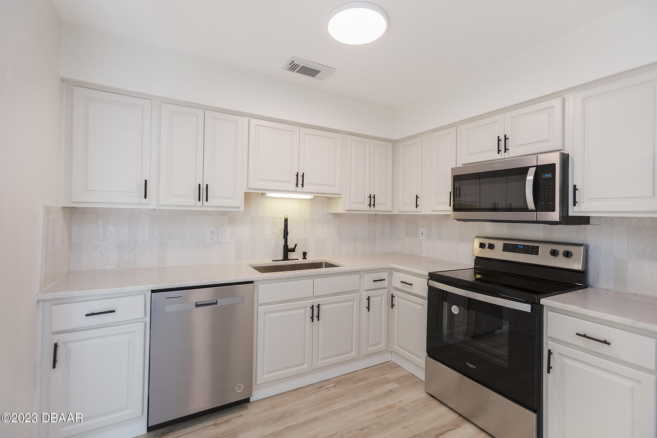 489 Wiltshire Boulevard Port Orange, FL 32127 - Photo 20 of 40 a kitchen with white cabinets and stainless steel appliances