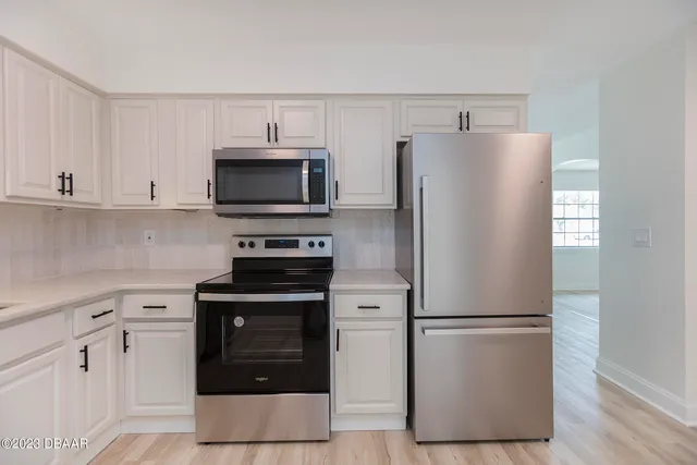 a kitchen with a refrigerator stove and white cabinets