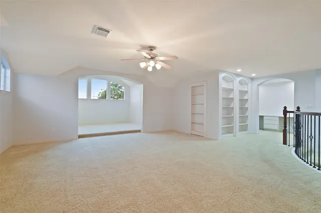 an empty room with windows and ceiling fan