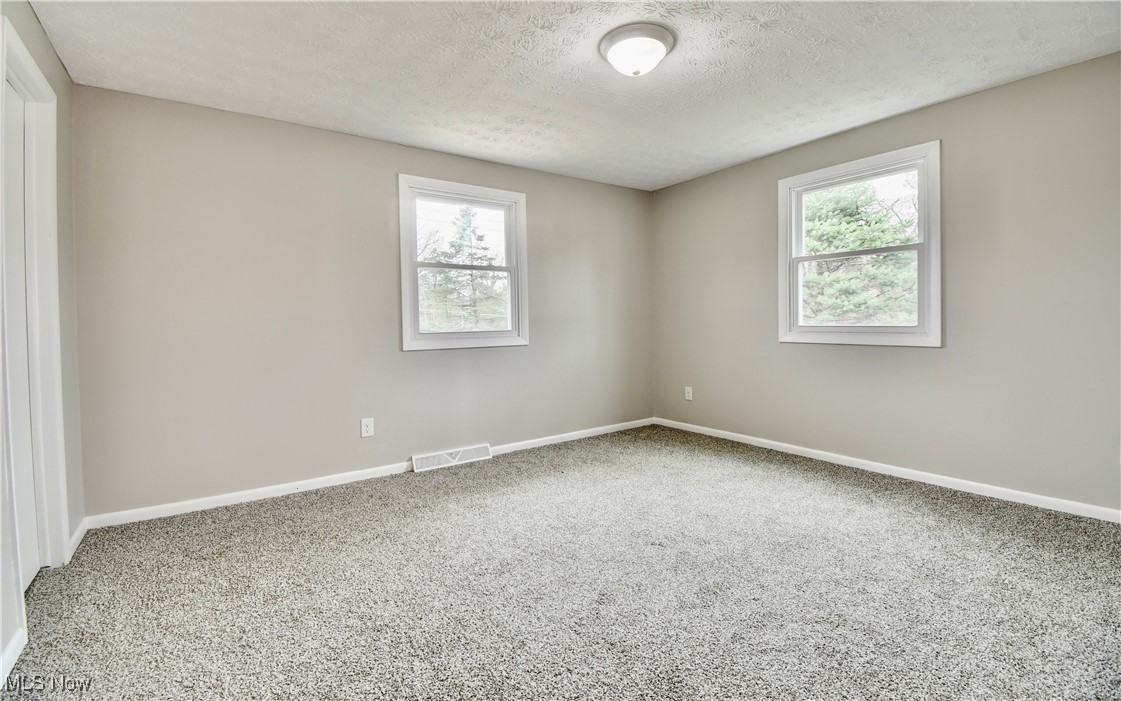 494 Moore Road Akron, OH 44319 - Photo 16 of 30 Unfurnished room with a textured ceiling, baseboards, carpet, and visible vents