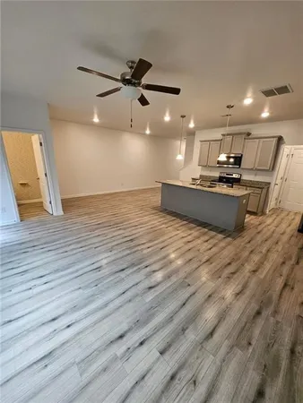 an empty room with wooden floor and a ceiling fan
