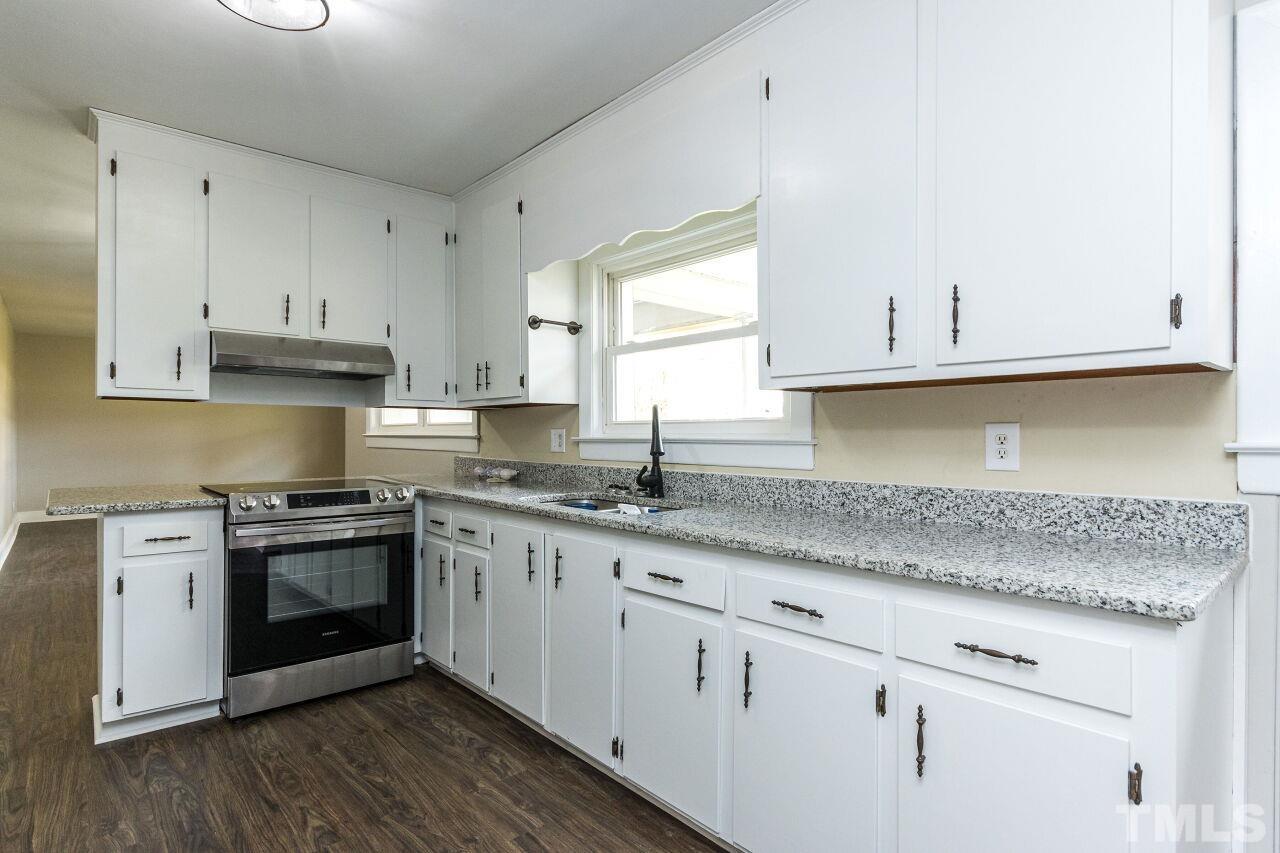 1309 Legend Road Raleigh, NC 27603 - Photo 11 of 27 a kitchen with granite countertop white cabinets and a stove with wooden floor