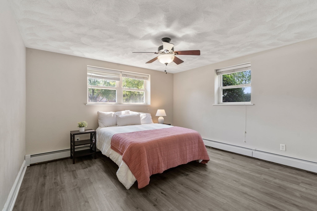 1105 Lexington Street, Unit 41 Waltham, MA 02452 - Photo 5 of 9 a bedroom with a bed chandelier and a window
