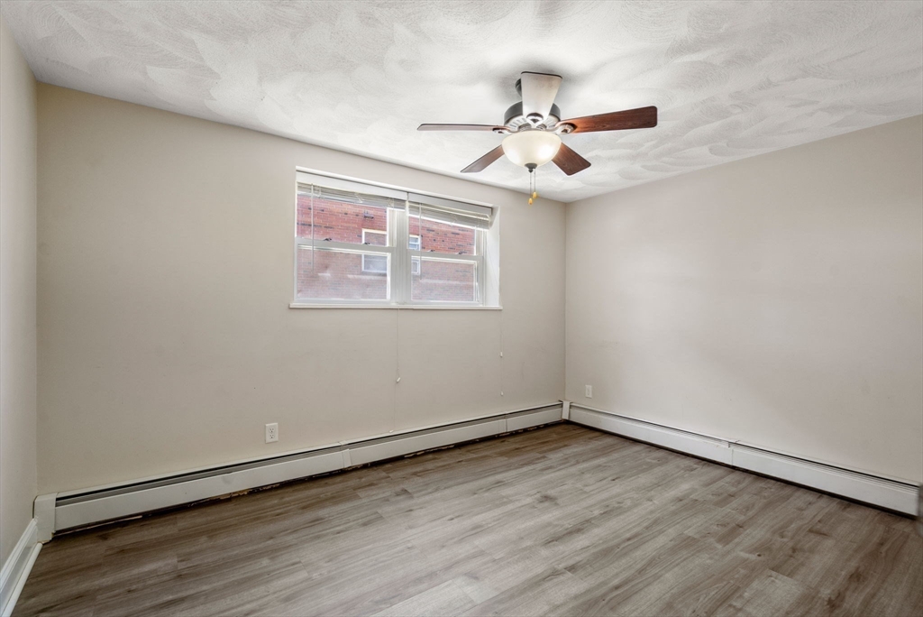 1105 Lexington Street, Unit 41 Waltham, MA 02452 - Photo 6 of 9 an empty room with wooden floor fan and windows
