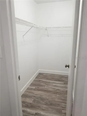 an empty room with wooden floor chandelier fan and windows