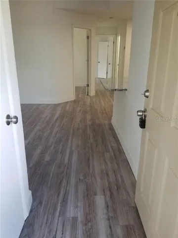 a view of a hallway with wooden floor and a ceiling fan