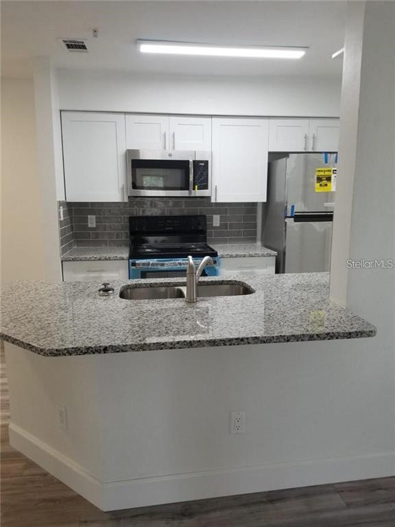 236 Afton Square, Unit 201 Altamonte Springs, FL 32714 - Photo 6 of 42 a kitchen with kitchen island granite countertop a sink a counter space and cabinets