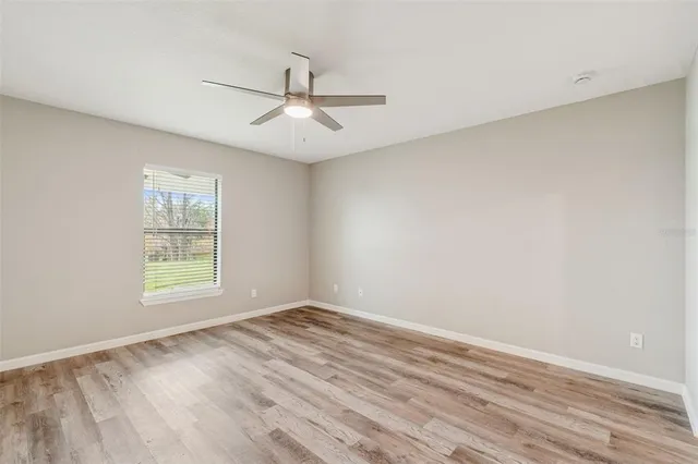 a view of an empty room with a window and wooden floor