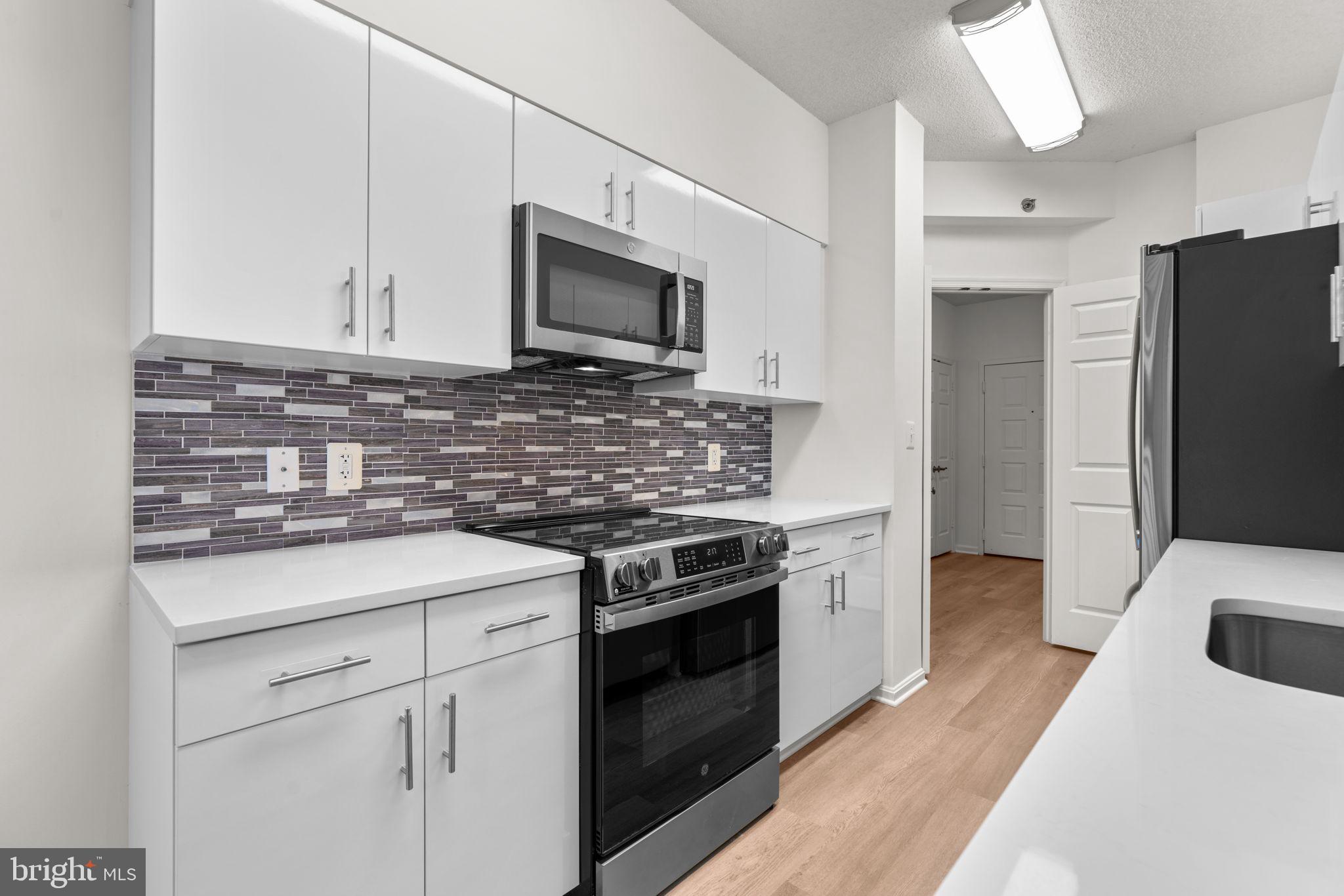 2901 South Leisure World Boulevard, Unit 233 Silver Spring, MD 20906 - Photo 13 of 43 a kitchen with stainless steel appliances granite countertop a stove microwave and refrigerator
