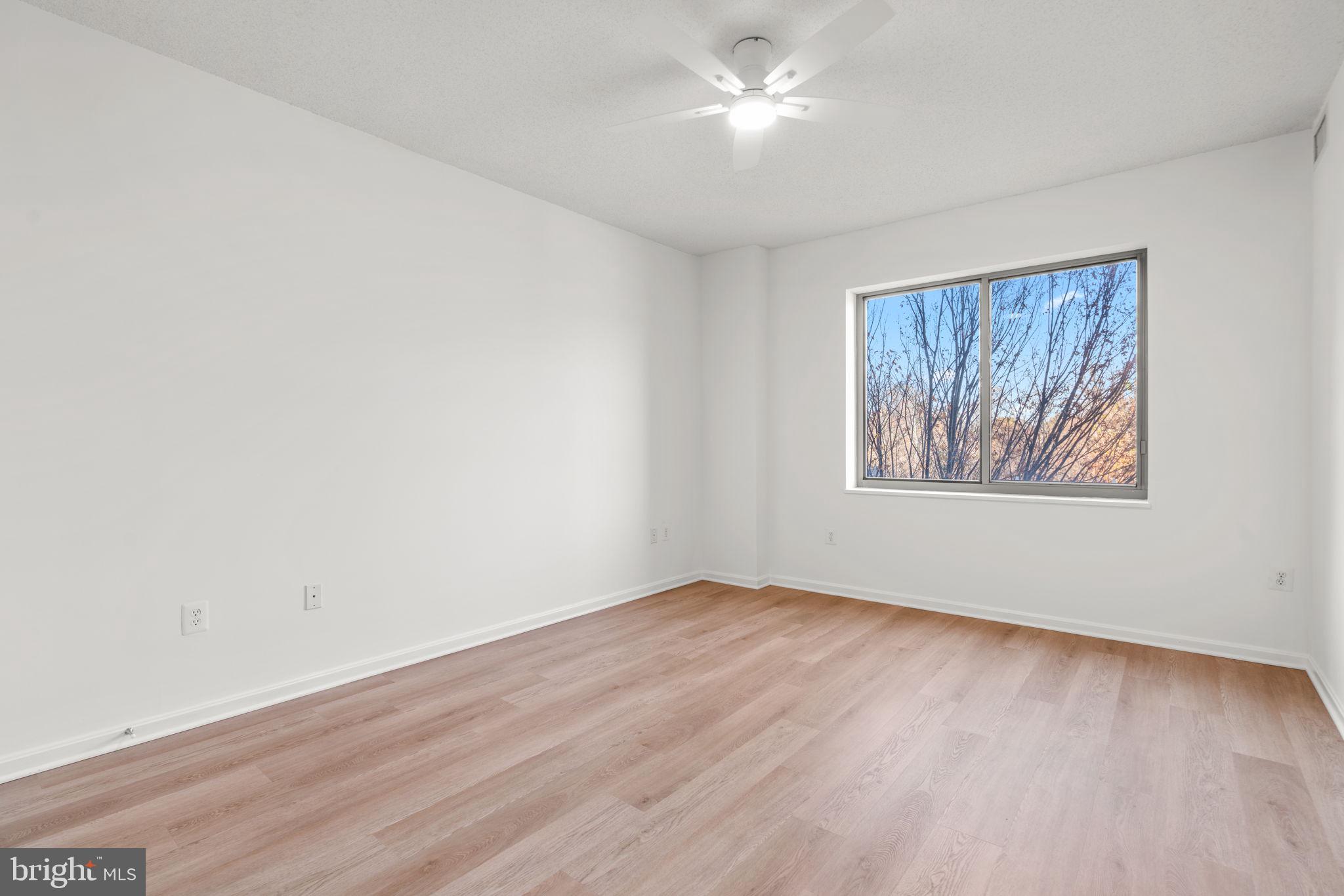 2901 South Leisure World Boulevard, Unit 233 Silver Spring, MD 20906 - Photo 21 of 43 an empty room with wooden floor chandelier fan and windows