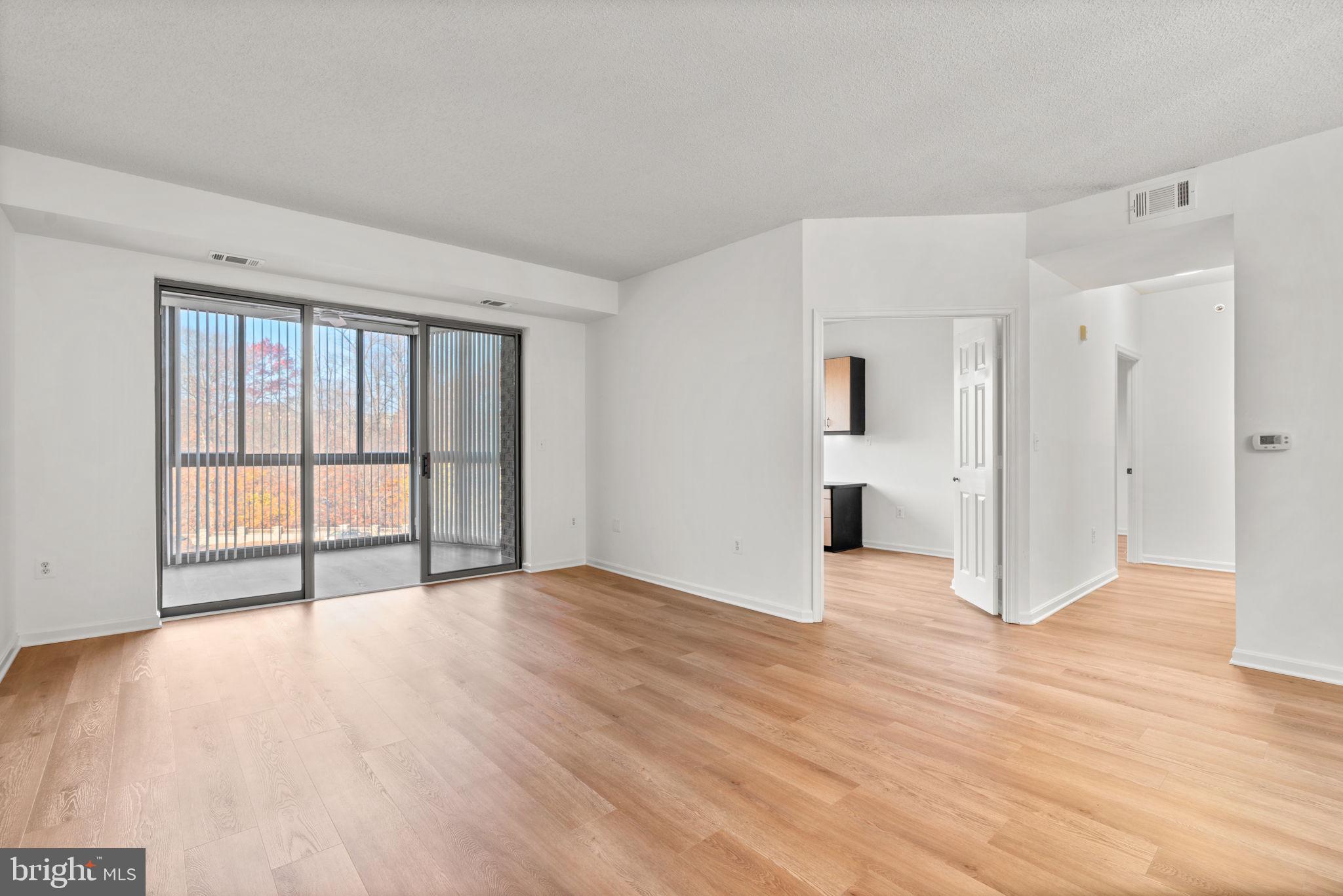 2901 South Leisure World Boulevard, Unit 233 Silver Spring, MD 20906 - Photo 5 of 43 a view of an empty room with wooden floor and a window