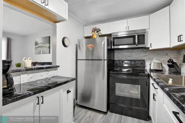 a kitchen with granite countertop a refrigerator stove and microwave