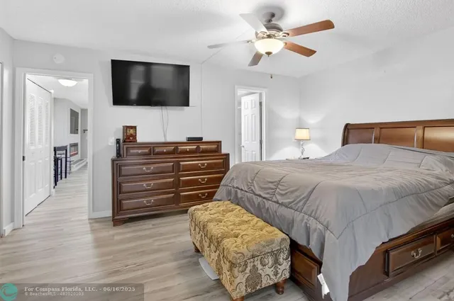 a bedroom with a bed a flat screen tv and a chandelier