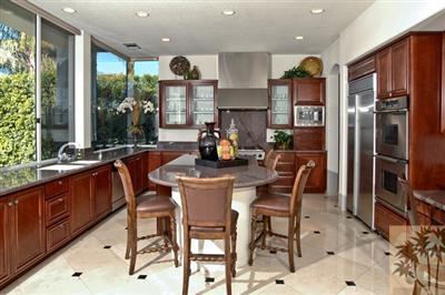 184 Loch Lomond Road Rancho Mirage, CA 92270 - Photo 7 of 13 a kitchen with stainless steel appliances granite countertop a refrigerator a sink dishwasher a dining table and chairs with wooden floor