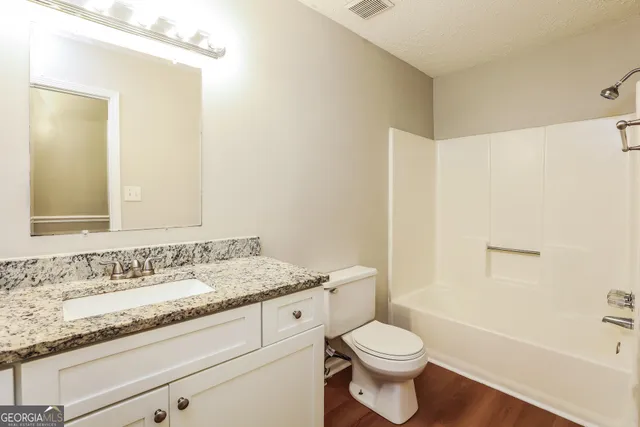 a bathroom with a granite countertop sink a toilet and a bathtub