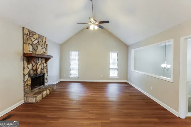 a view of an empty room with window and wooden floor