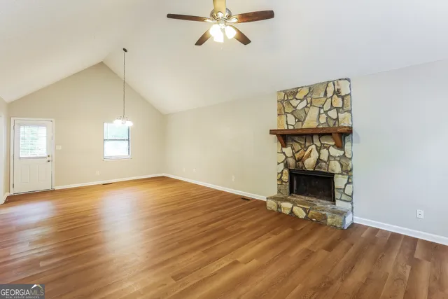 an empty room with wooden floor fan and windows