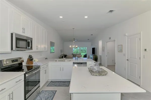 a kitchen with a sink dishwasher stove and white cabinets with wooden floor