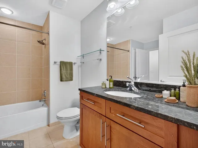 a bathroom with a granite countertop sink a toilet a mirror and shower