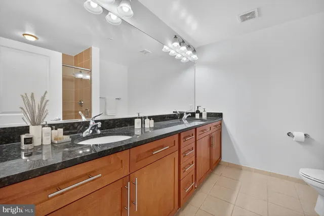a bathroom with a granite countertop sink a toilet and mirror