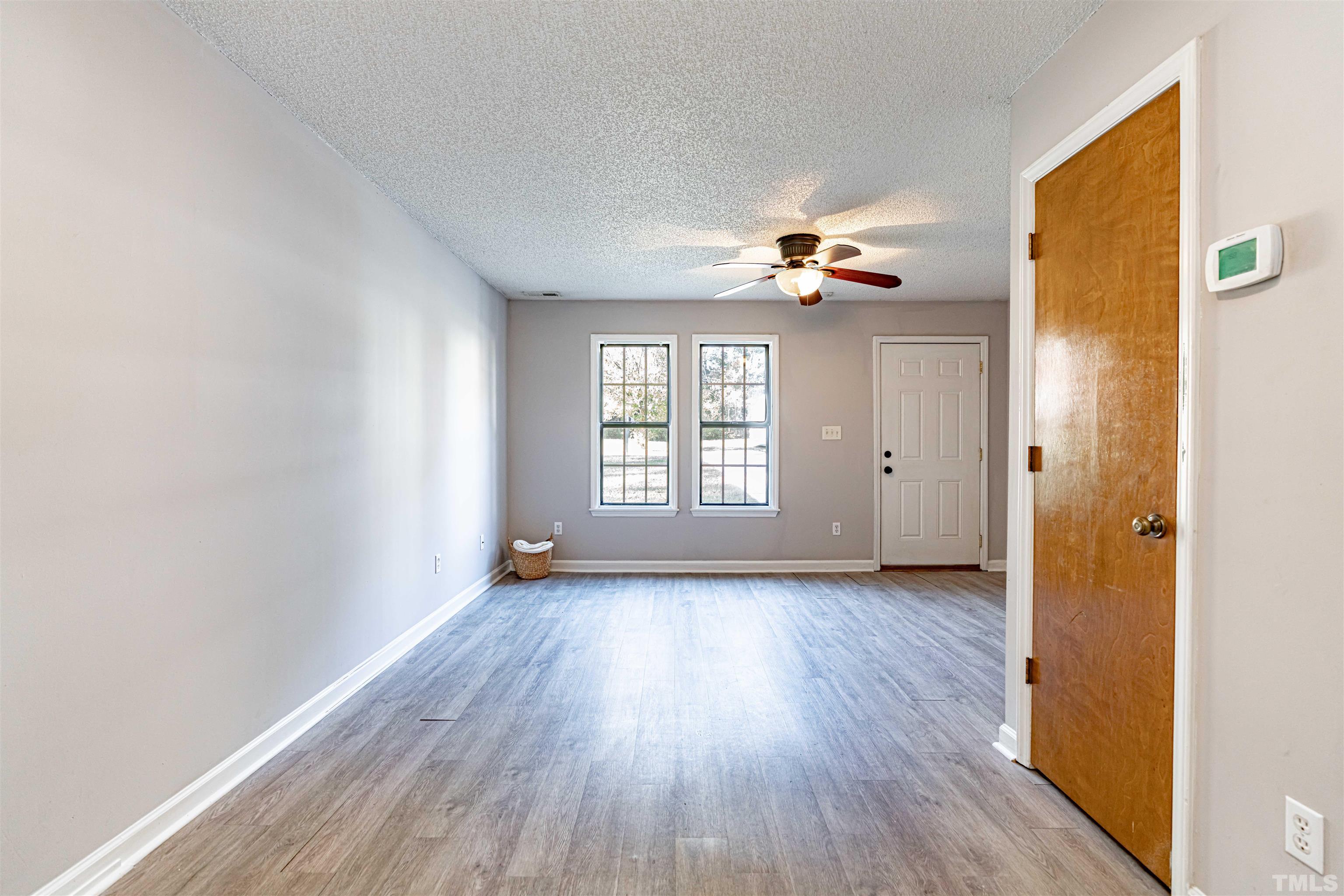1722 Fox Hollow Drive Raleigh, NC 27610 - Photo 6 of 18 an empty room with wooden floor chandelier fan and windows