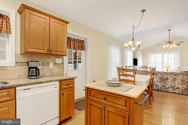 a kitchen with kitchen island granite countertop a sink cabinets and wooden floor